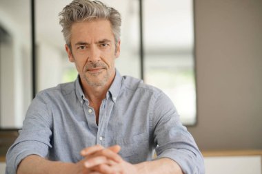 Çağdaş evde kameraya bakan yakışıklı olgun adam Portresi