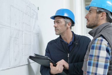 Mimar ve inşaat işçisi proje planı üzerinden gidiyor