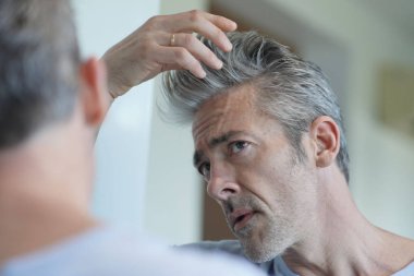 Evde aynaya bakan olgun yakışıklı adam Portresi