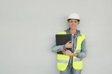 Gri arka planda güvenlik dişli gülümseyen kadın inşaat işçisi