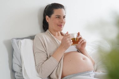Hamile kadın yatakta yatan ve infüzyon içme