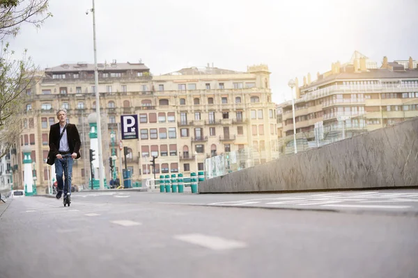 Businessman on daily commute riding micro scooter