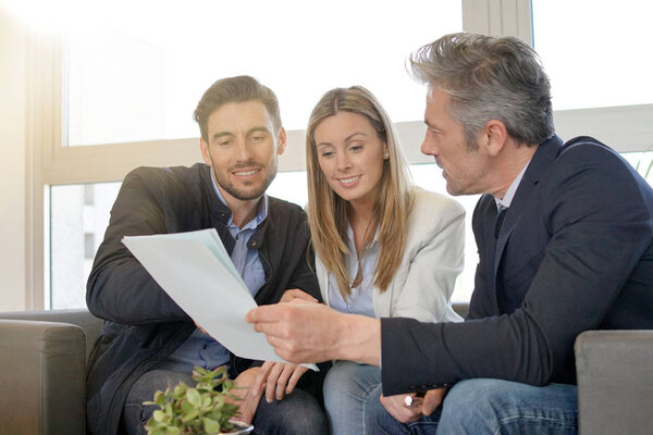 Couple looking over buyers agreement with real estate agent