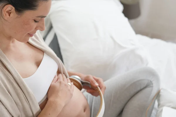 Pregnant woman having her baby listening to music through headphones