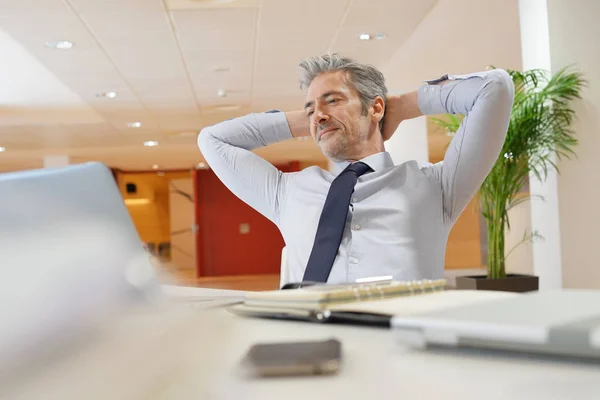 オフィスのデスクでリラックスする成熟したビジネスマン — ストック写真