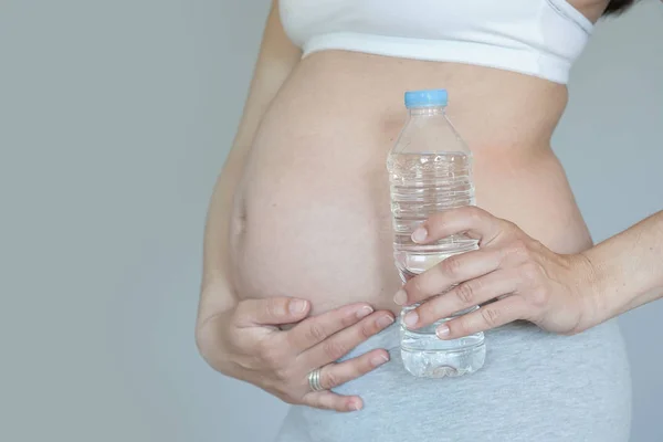 Крупный План Беременной Женщины Живот Бутылка Воды — стоковое фото