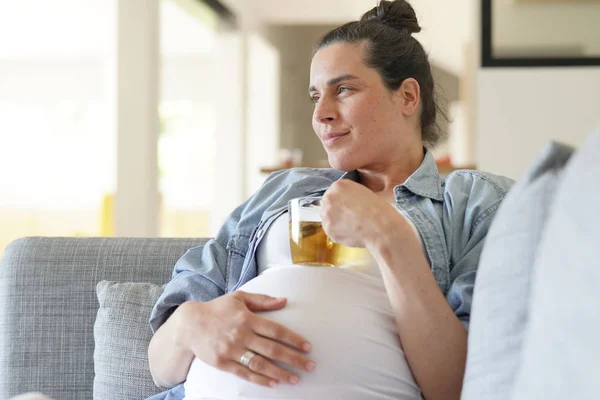 Pregnant woman relaxing in sofa drinking hot tea