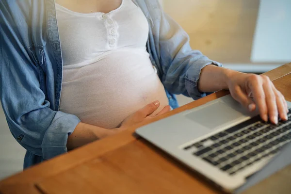 オフィスで妊娠中の女性の腹とラップトップのクローズアップ — ストック写真