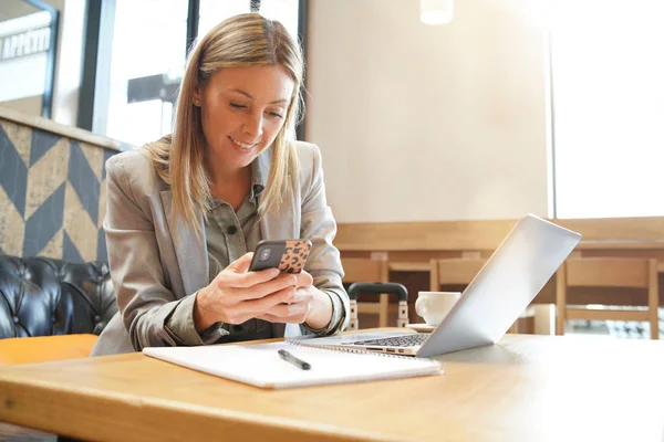 Saleswoman checking cellphone on business trip