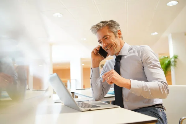 現代のオフィスで携帯電話で話す成熟したビジネスマン — ストック写真