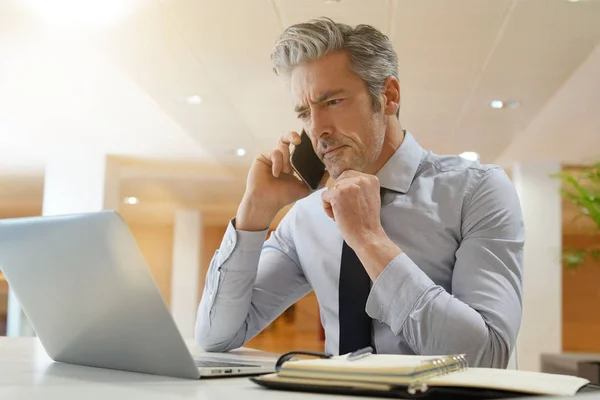 現代のオフィスで携帯電話で話す成熟したビジネスマン — ストック写真