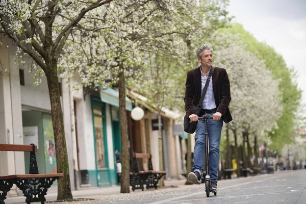 Businessman on daily commute riding micro scooter