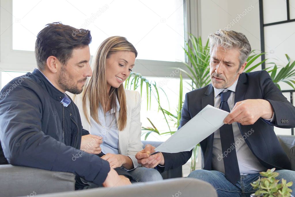 Couple looking over buyers agreement with real estate agent