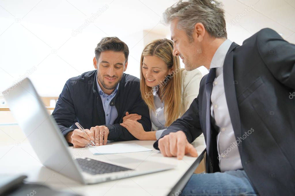 Couple signing contract with real estate agent