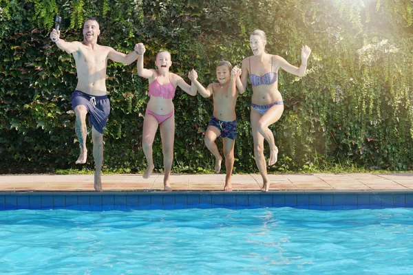 スイミングプールでジャンプ陽気な家族 — ストック写真
