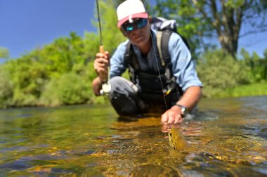 Yazın uçan balıkçılar dağ nehrinde alabalık avlıyor.
