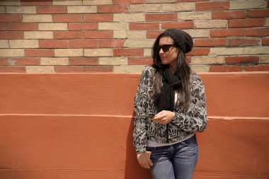 Tuğla duvarda dikilen modaya uyan kadın