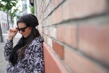 Tuğla duvarda dikilen modaya uyan kadın