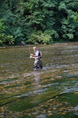 İnsanoğlu yazın temiz suyla güzel bir nehirde balık tutar.