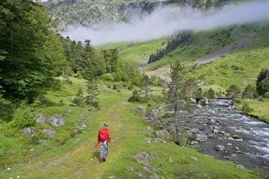 Uçan balıkçı alabalığı, yaz aylarında yüksek dağlarda yürüyüş çantası ve turuncu bir ceketle balık tutuyor.