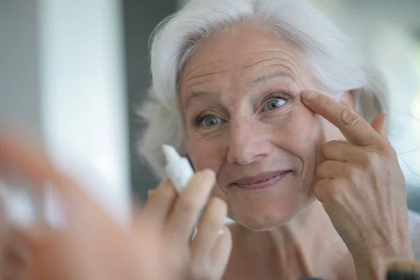 鏡を見ながら肌の世話をする先輩女性の肖像画 — ストック写真