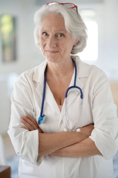 Portrait of senior doctor woman with stethoscope and white uniform, looking at camera