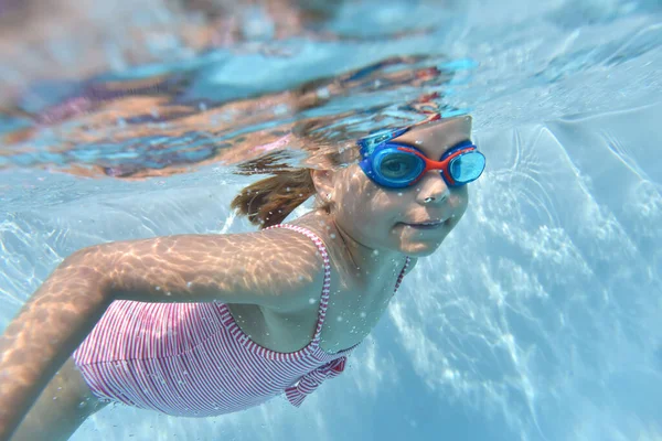 プールの水の下で泳ぐゴーグルとかわいい女の子の肖像画 — ストック写真