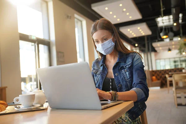 Mujer Joven Sentada Cafetería Trabajando Ordenador Portátil Con Máscara Facial —  Fotos de Stock