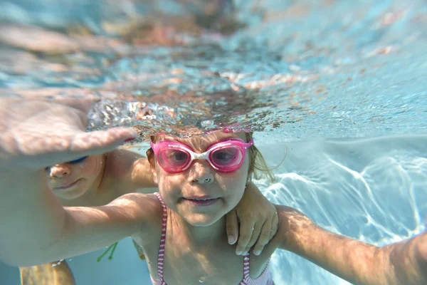 プールの水の下で泳ぐゴーグルとかわいい女の子の肖像画 — ストック写真