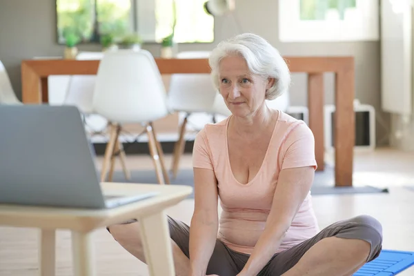 Senior woman doing fitness exercises from home- virtual classes