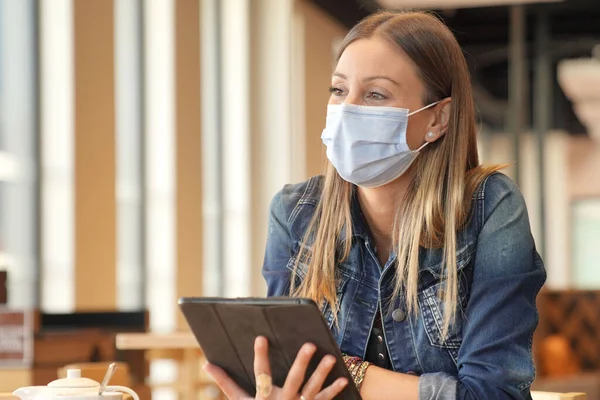 Młoda Kobieta Siedzi Kawiarni Pracuje Nad Cyfrowym Tabletem Maską Twarzy — Zdjęcie stockowe