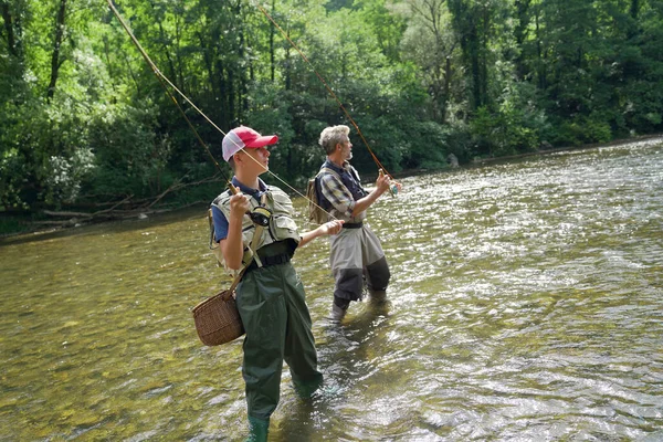 父と息子は夏に澄んだ水のある美しい川で釣りをする — ストック写真