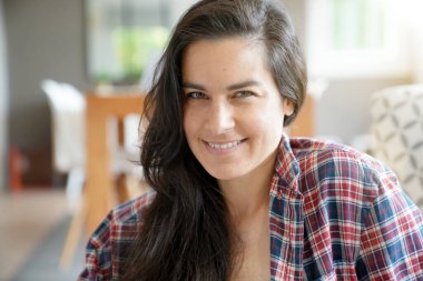 Güzel ve gülümseyen siyah saçlı bir kadının portresi evde dinleniyor.