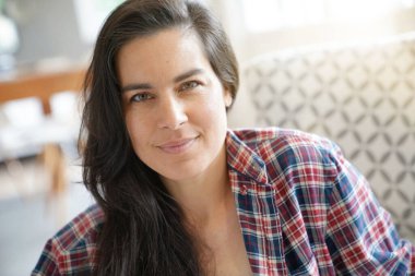 Güzel ve gülümseyen siyah saçlı bir kadının portresi evde dinleniyor.