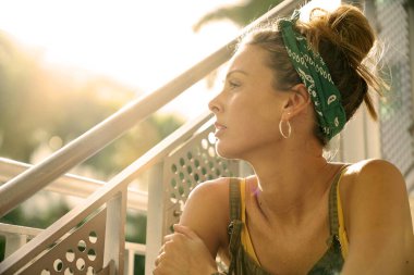 Şehir tarzı çekici genç bir kadın beton merdivenlerde oturuyor.