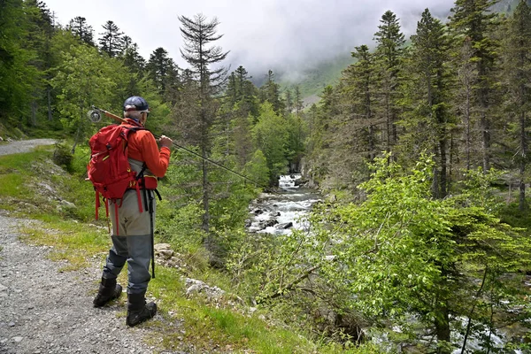 夏は高い山の中でリュックとオレンジのジャケットを持ったハイキングでマス釣りをしています — ストック写真