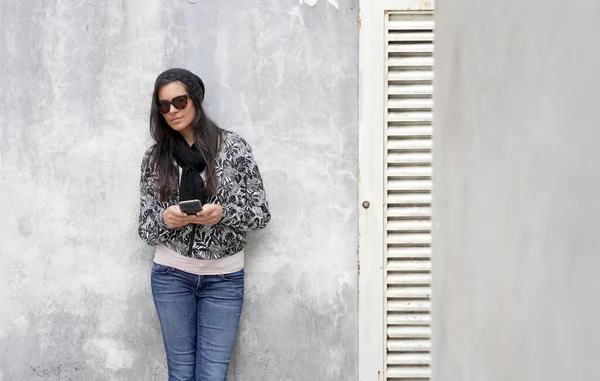 Trendy Vrouw Met Een Zwarte Zonnebril Betonnen Muur Smartphone — Stockfoto