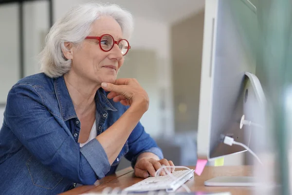Senior woman working on desktop computer at home