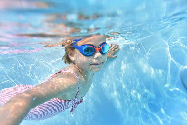 プールの水の下で泳ぐゴーグルとかわいい女の子の肖像画 — ストック写真
