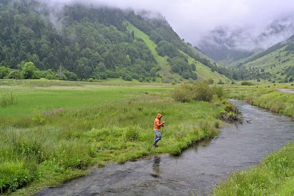 Turuncu Ceketli Bir Balıkçı Yağmurlu Havada Dağlarda Alabalık Avlıyor — Stok fotoğraf