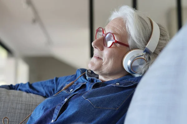 Seniorin Mit Tablet Und Kopfhörer Auf Sofa Entspannt — Stockfoto