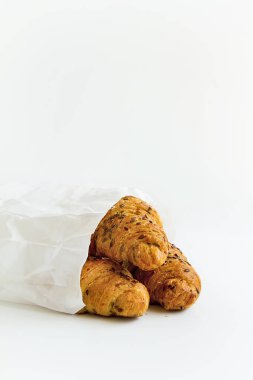 tohumlar üzerinde beyaz bir tablo pişirme yüzeyinde bir beyaz kağıt torba ile üç lezzetli kruvasan kruvasan üzerinde odaklanmak