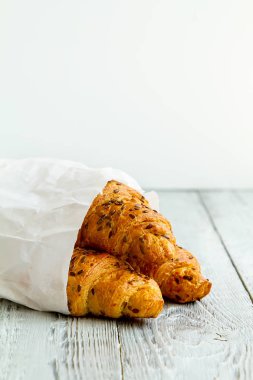 tohumlar üzerinde ahşap bir masa pişirme yüzeyinde bir beyaz kağıt torba ile üç lezzetli kruvasan kruvasan üzerinde odaklanmak