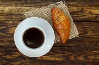 beyaz fincan sıcak kahve ve çörek Karanlık bir ahşap tablo