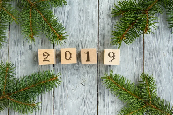 New year\'s holiday card. wooden cubes with figures of the year on a gray wooden background, next to fir branches