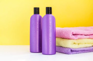 iki mor Kozmetik Şişeler ve Spa uygulamaları ve vücut ve saç bakımı için üç banyo havlusu