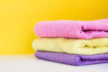 üç çok renkli Terry havlu beyaz arka planda sarı bir duvar var