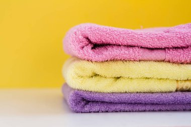 üç çok renkli Terry havlu beyaz arka planda sarı bir duvar var