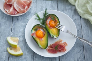 Beyaz bir daire ve iki limon yarım yumurta ile iki pişmiş avokado yarısını. Ahşap masa, kopya alanı, üstten görünüm üzerinde sağlıklı kahvaltı