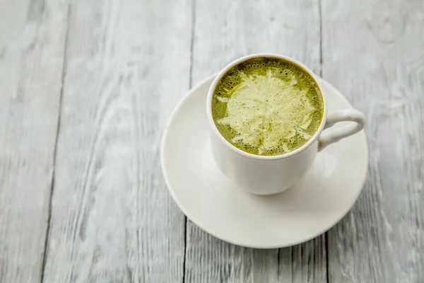 Taza de té verde matcha caliente con leche sobre fondo de madera gris — Foto de Stock